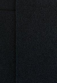 Schwarzer, strukturierten Stoff mit einer weichen, saugfähigen Oberfläche und einem geschlungenen Design. Das Material wirkt dicht und plüschig, geeignet für Handtücher.