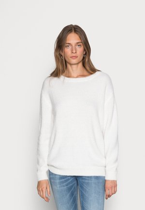 Weißer, flauschiger Pullover mit weitem Ausschnitt und tiefen Schultern. Weiche Textur, lange Ärmel und lockere Passform. Getragen mit hellblauen Jeans.