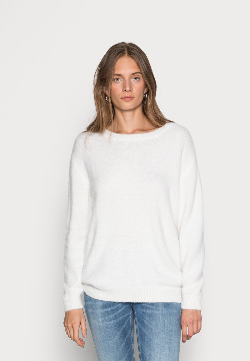 Valge, pehme kampsun laia kaelusega ja langetatud õlgadega. Pehme tekstuur, pikad varrukad ja mugav istuvus. Kantud helesiniste teksadega.