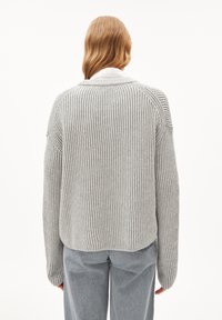 Suéter gris de canalé con un corte relajado y mangas anchas. Presenta un dobladillo redondeado y un patrón de punto texturizado. Líneas verticales sutiles a lo largo.