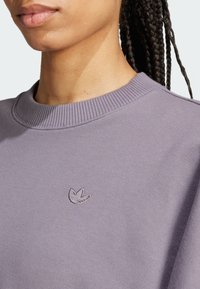 Felpa viola con collare a costine e logo ricamato sul petto, caratterizzata da una texture liscia e una vestibilità ampia.