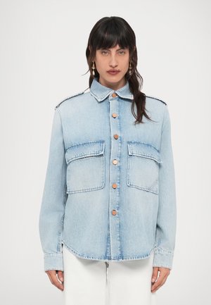 Svetlomodrá rifľová bunda s dvoma náprsními vreckami, zapínaním na kovové gombíky a klasickým golierom s jemným detailom na ramenách.