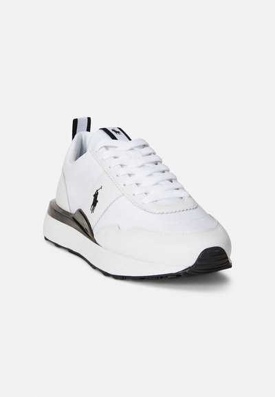 Λευκό αθλητικό παπούτσι με υφή στο πάνω μέρος, μαύρες λεπτομέρειες, δέσιμο με κορδόνια και αντίθετη γκρι σόλα. Διαθέτει λογότυπο στο πλάι και θηλιά για να το κρατάτε.