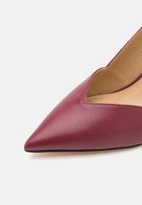 Escarpin pour femme en cuir bordeaux à bout pointu avec un décolleté en V et une doublure intérieure beige sur fond blanc.