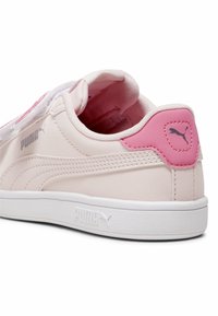 Baskets roses avec une tige en synthétique lisse, semelle blanche, accents texturés et un col rembourré. Présente un logo sur le talon et le côté.