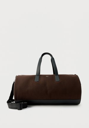 Sötétbarna henger alakú utazótáska fekete fogantyúkkal, állítható vállpánttal és a középen elhelyezkedő kis "BOSS" logóval.