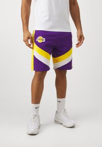 Bermudas de baloncesto moradas y amarillas con rayas en zigzag blancas, con el logo de Los Angeles Lakers en el muslo izquierdo. Material de algodón.