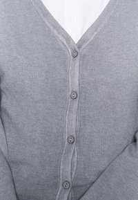 Cárdigan gris con un diseño de escote en V, que presenta un patrón de punto texturizado y seis botones grises dispuestos a lo largo del frente.