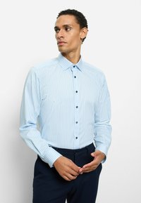 Hellblau gestreiftes Hemd mit Knopfleiste am Kragen, langen Ärmeln und dunklen Knöpfen. Glatter Stoff und taillierte Passform, kombiniert mit dunkler Hose.