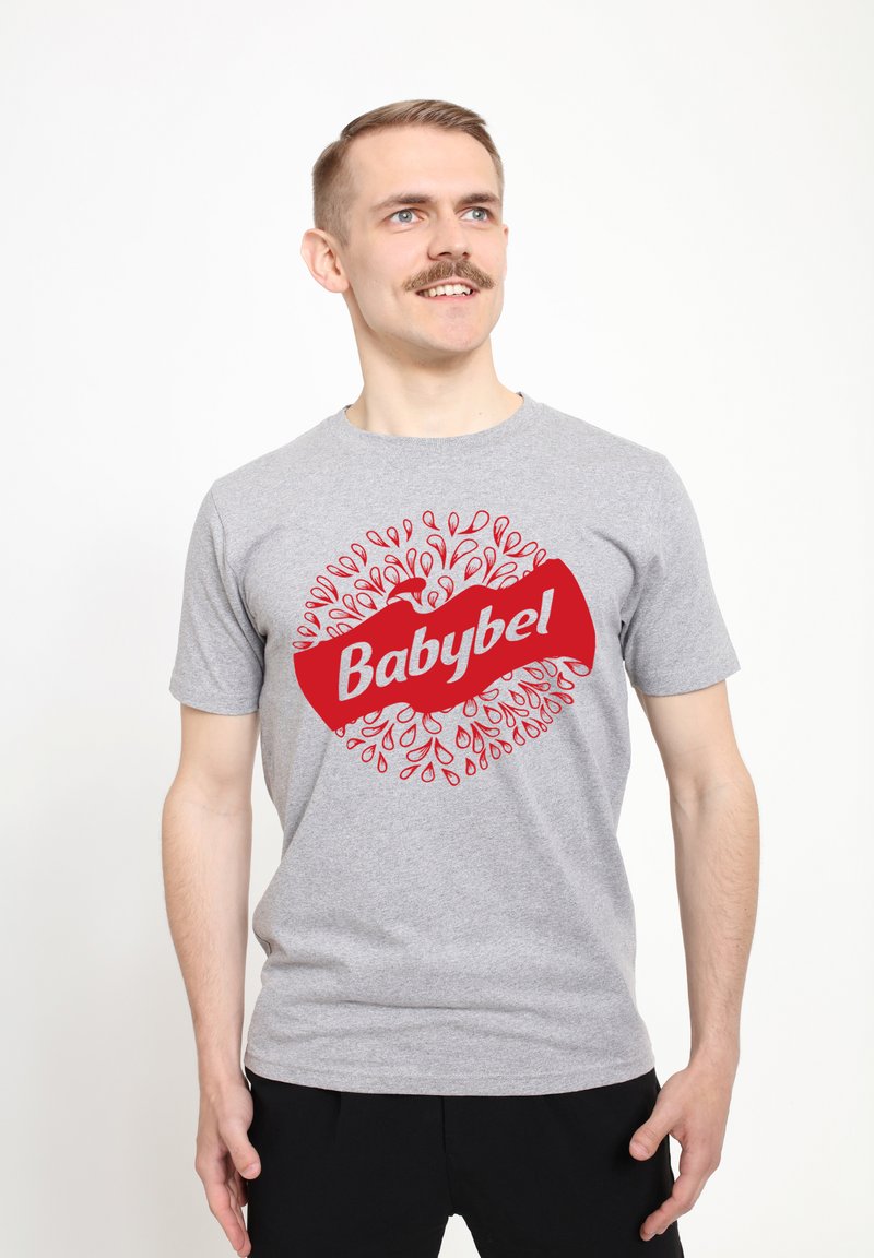Šedé bavlněné tričko s velkým červeným logem "Babybel" a kruhovým designem malých červených kapek okolo něj. Krátké rukávy a kulatý výstřih.