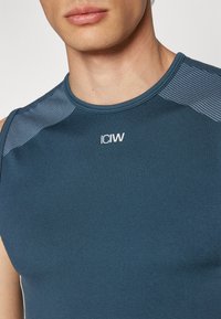 Mørkeblå ærmeløs treningsskjorte med teksturert grå aksent på skuldrene. Har logoen "ICIW" trykt i hvitt på fronten.