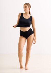 Zwarte tanktop met brede schouderbanden en een aansluitend ontwerp, gecombineerd met hoge zwarte slipjes. Glad stoftextuur, minimalistische stijl.