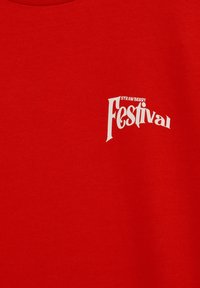 Tissu rouge avec le texte blanc "Festival de la Fraise" imprimé en police stylisée sur le côté supérieur gauche.