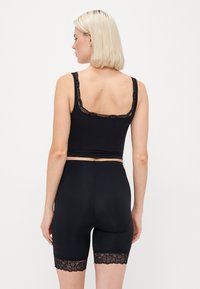 Black lace-trimmed camisole and high-waisted shorts. Smooth fabric with floral lace accents at the neckline and hem.