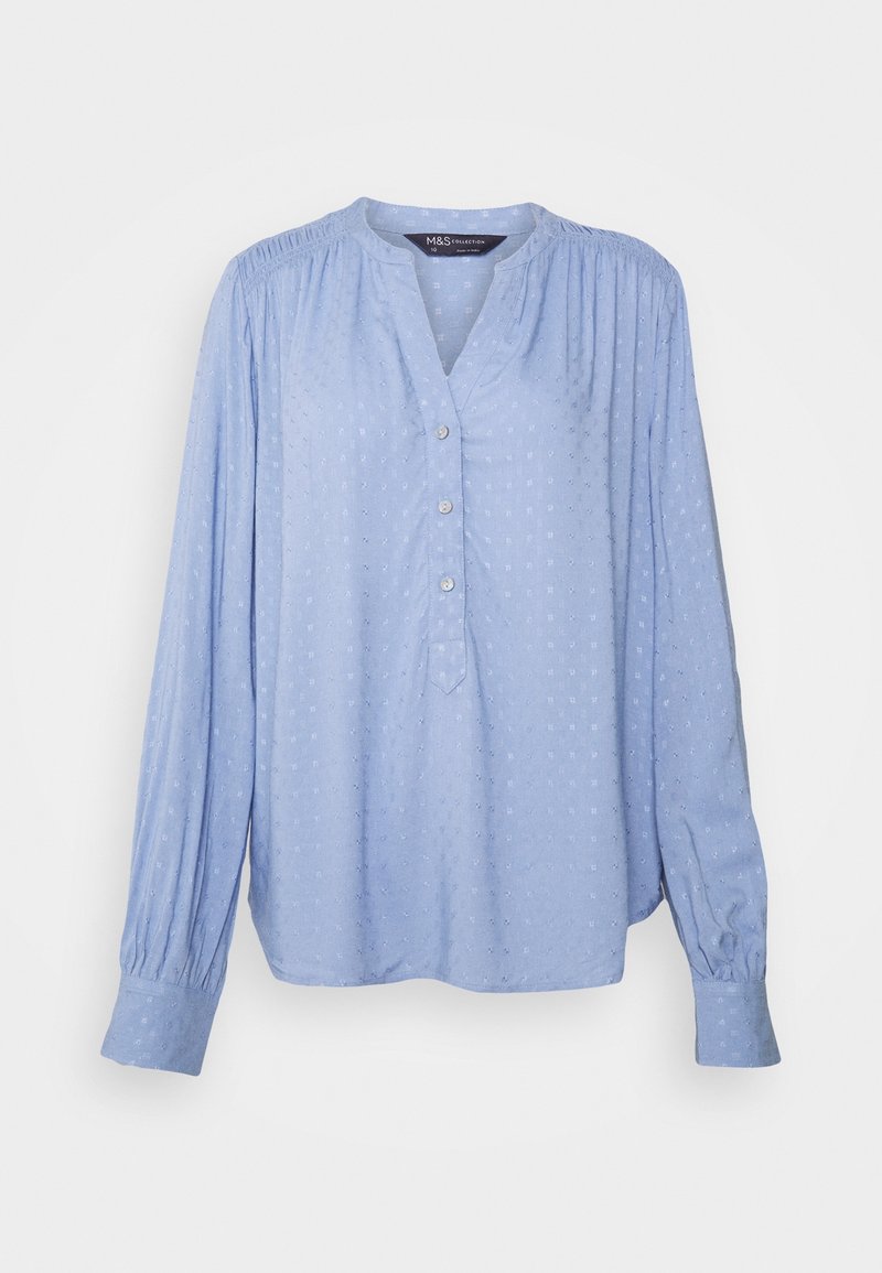 Blouse à manches longues bleu clair avec un motif texturé subtil, trois boutons sur la patte de boutonnage avant, épaules froncées et poignets boutonnés.
