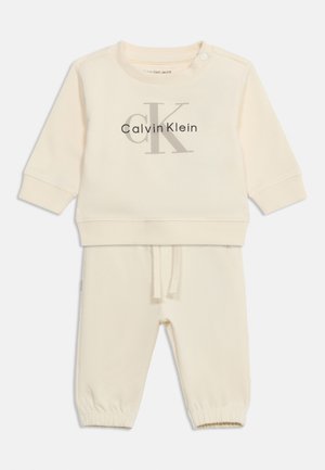 Kremowy komplet dla niemowląt z bluzą i spodniami, z logo Calvin Klein na piersi, z zatrzaskami na ramieniu i sznurkiem w talii.