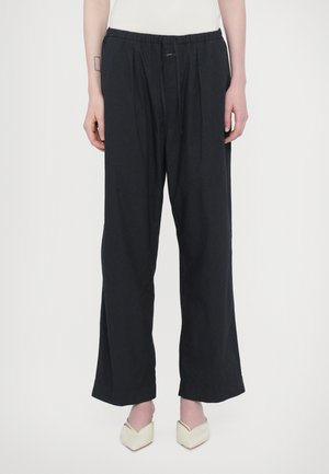 Zwarte, wijde broek van een zachte stof met een elastische tailleband en voor plooien. Heeft een casual, ontspannen pasvorm en schone zomen.