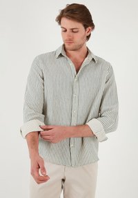Camisa ligera de cuadros en colores azul y crema, con cuello y mangas remangadas. Textura de mezcla de algodón.