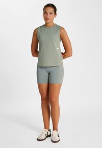 Lichtgroene mouwloze top en bijpassende short van een zachte, rekbare stof. Heeft een eenvoudig ontwerp met een klein logo op het shirt.