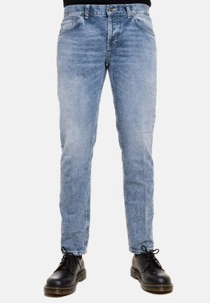 Jeans in denim blu chiaro con una vestibilità slim, dotati di tasche frontali, chiusura a zip e una texture leggermente sbiadita. Abbinati a scarpe nere con lacci.