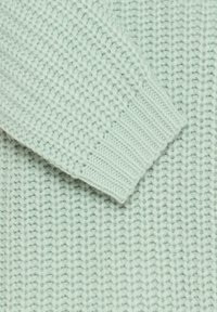 Jersey de punto verde claro con puños acanalados y un patrón de espiguilla texturizado, que muestra una apariencia suave y acogedora.