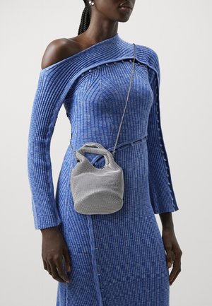 Blauwe geribbelde jurk met een off-shoulder ontwerp en knoopaccenten, gecombineerd met een zilveren mesh handtas met een gebogen handvat.