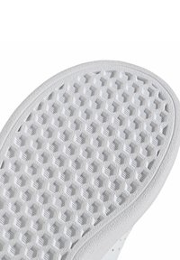 Semelle de chaussure blanche texturée présentant un motif hexagonal et des sections surélevées pour l'adhérence. Bords arrondis et contours de surface lisses visibles.