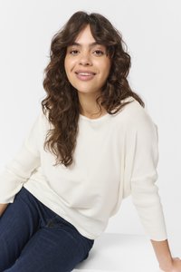 Cremefarvet strikket sweater med en afslappet pasform og ¾ lange ribbede ærmer, kombineret med mørkeblå jeans. Blød tekstur med minimale detaljer.