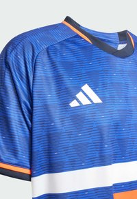 Blå atletisk trøje med et geometrisk mønster, orange og hvide accenter, rund hals og Adidas-logoet i hvidt foran.
