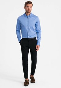 Blauwe overhemd met lange mouwen en een gestructureerde kraag, gecombineerd met slim-fit zwarte broeken en een paar bruine suède schoenen.