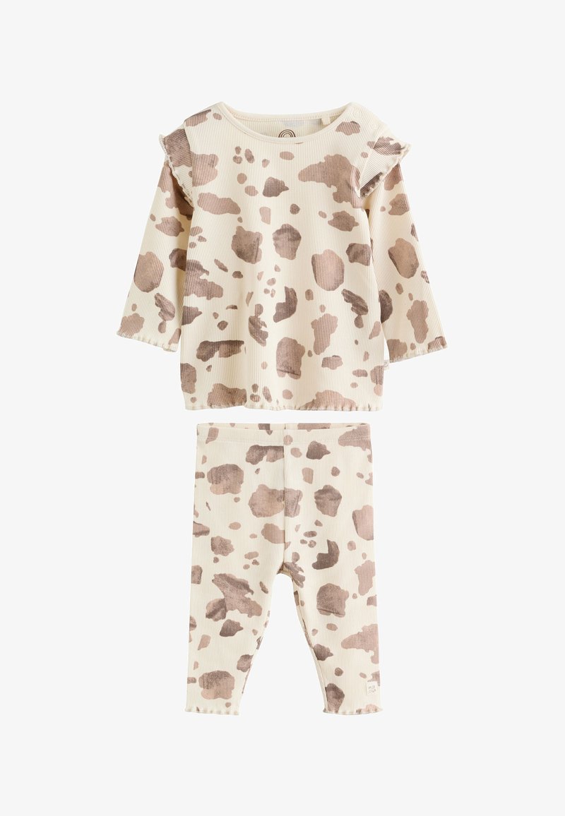 Ensemble haut à manches longues crème et pantalon avec motif taches de vache marron et détails volants aux épaules, texture de tissu côtelé.