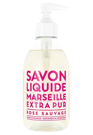 Savon liquide clair dans une bouteille en plastique transparent avec pompe. Étiquette en texte rose vif, indiquant "Savon Liquide Marseille Extra Pur Rose Sauvage."