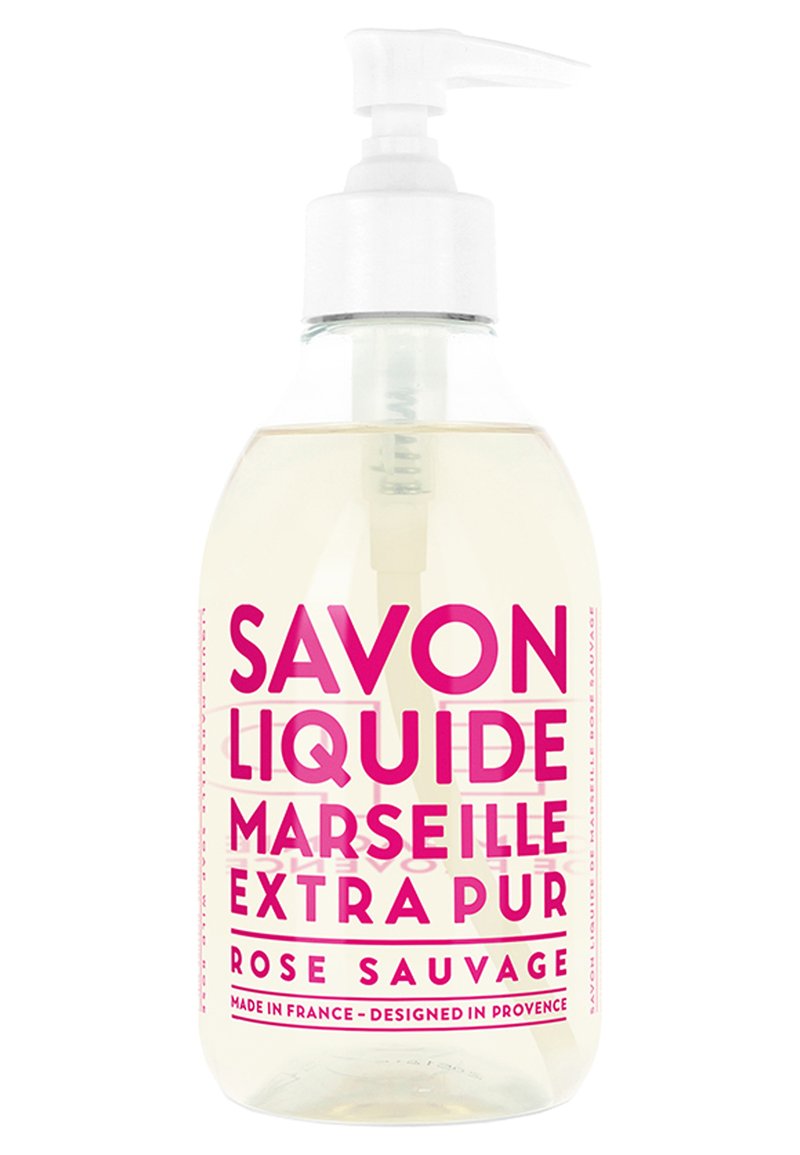 Savon liquide clair dans une bouteille en plastique transparent avec pompe. Étiquette en texte rose vif, indiquant "Savon Liquide Marseille Extra Pur Rose Sauvage."