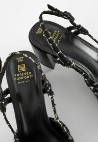 Sandales à talons blocs noires avec lanières tissées et semelles intérieures rembourrées portant la mention "Forever Comfort Wide Fit", taille 6½W 40W, sur un fond gris.