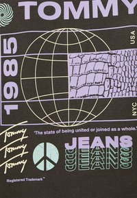 Design grafico e testuale che presenta "TOMMY 1985", un globo in wireframe con texture di pelle di rettile, ripetute firme "Tommy", simbolo della pace e il testo "JEANS".