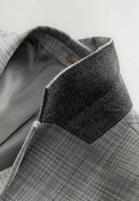 Blazer a cuadros grises con un collar de fieltro negro, que cuenta con un forro suave y detalles de costura limpios.