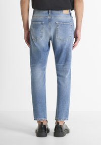 Jeans de mezclilla azul claro con un corte relajado, cinco bolsillos y un diseño de pierna recta. Presentan costuras visibles y una etiqueta de cuero en la parte trasera.