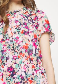 Vestido floral con un patrón multicolor en tonos de rosa, verde y púrpura, fabricado con tejido transpirable, escote redondo y mangas cortas.