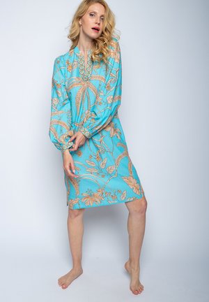 Een turquoise jurk met een bloemen- en bladerenpatroon in beige, lange ballonmouwen en een ronde halslijn met decoratieve afwerking.