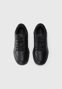 Black sneakers with smooth leather and mesh accents, featuring perforations on the toe and side, and lacing system. Red logo on the insole.