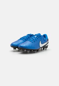Blue football boots with a textured design, featuring white Nike accent on the side and black studs on the sole for traction.