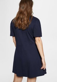 Vestido de manga corta azul marino en tejido ligero, de corte suelto, con falda acampanada. Presenta un diseño sencillo y una textura suave.