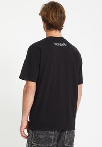 Czarna bawełniana koszulka z krótkim rękawem, z okrągłym dekoltem i haftowanym na białą kolorze logo Volcom na plecach. Luźny krój.