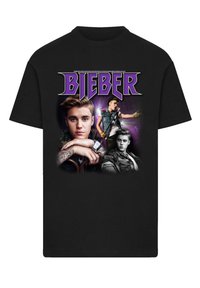 Black cotton t-shirt featuring a collage of images, including three portraits, with the word "BIEBER" in bold purple lettering above.