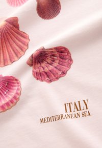 Tissu en coton avec des imprimés de coquilles Saint-Jacques roses et un texte doré indiquant "ITALIE MER MÉDITERRANÉE." Texture lisse, fond clair.