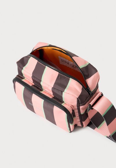 Μικρή ριγέ ροζ και καφέ τσάντα crossbody με μπροστινή τσέπη με φερμουάρ και μερικώς ανοιχτό κύριο διαμέρισμα με φερμουάρ που δείχνει πορτοκαλί εσωτερικό.