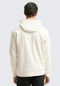 Cremfarbener Hoodie mit lässiger Passform, mit einer Zugkordelkapuze, geripptem Saum und Bündchen sowie einem glatten, strukturierten Stoff.