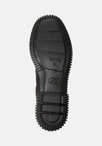 Suola in gomma nera di una scarpa con scanalature profonde, con il logo "Camper" e la taglia "38" impressi sulla superficie.