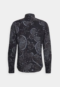 Chemise à manches longues avec une base noire et de grands motifs floraux gris. La texture du tissu semble douce, avec un col standard et des poignets à boutons.