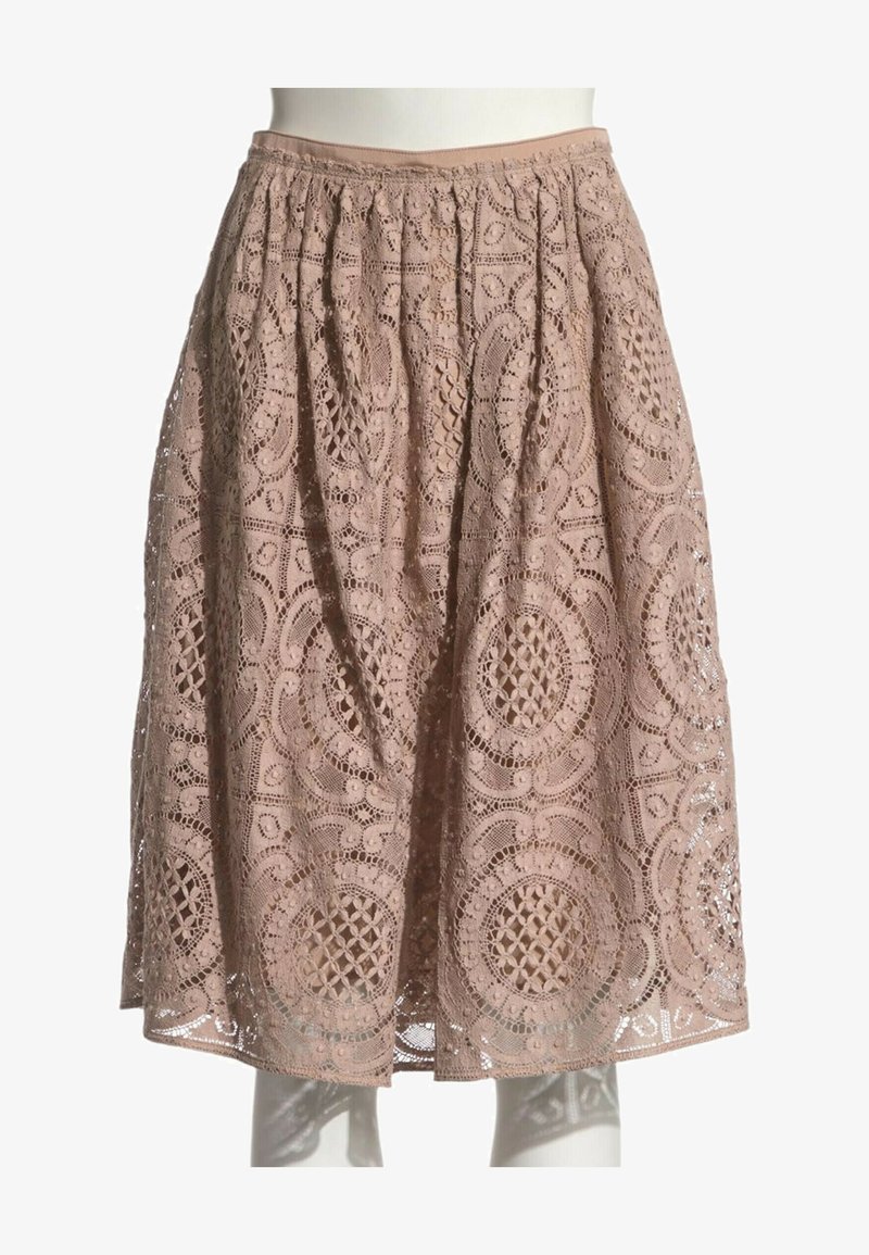 Jupe beige en dentelle jusqu'au genou avec des motifs circulaires et floraux complexes et une ceinture froncée, présentée sur un mannequin blanc.